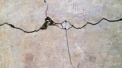 A close up view of cracked concrete surface with visible texture and small debris