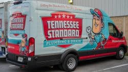 A van with "Tennessee Standard Plumbing & Drain" branding, featuring a cartoon plumber holding a wrench and the website TNStandard.com—ready to fix sudden drops in water pressure.