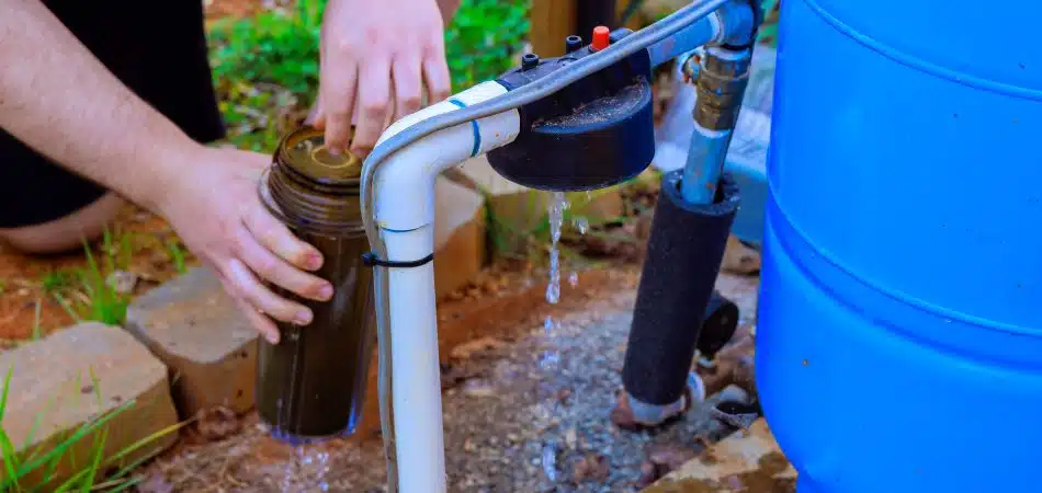 Individual changing filter water from water filtration system, showcasing sustainability in an urban backyard.