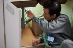 Home service worker checking pipes under kitchen sink