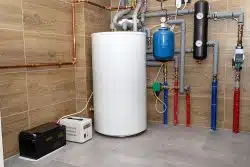 Modern gas boiler room lined with ceramic tiles imitating wood, visible emergency power supply with a 12 volt battery.