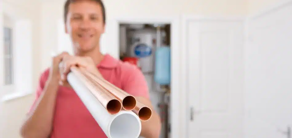 man golding a copper pipes and a PEX pipe