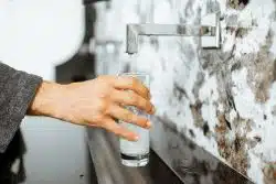 A person fills a clear glass with water.