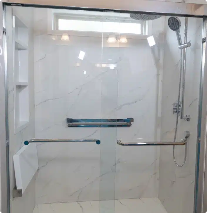 walk-in shower featuring a frameless glass door, white marble-style tiled walls, and built-in shelving