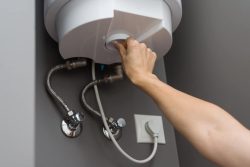 Woman hands setting temperature of water in heater electric boiler.