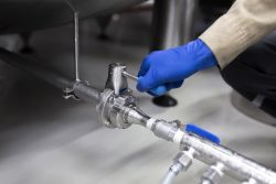 a worker's hand turning the water valve of a pipeling on the factory
