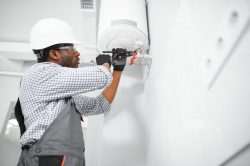 Young African Male Plumber Repairing Boiler.